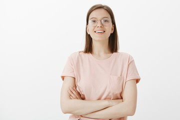 Fototapeta premium Horizontal shot of confident smart caucasian female in trendy glasses, holding hands crossed on chest and gazing with self-assured expression at camera, ready to solve any problem on her way
