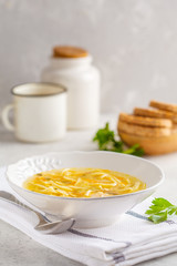 Homemade chicken noodle soup in a white plate, white background.