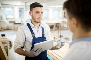 Young man in workwear consulting with his colleague while searching for online working ideas