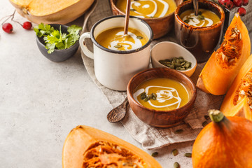 Autumn pumpkin soup puree with cream in cups, the autumn scenery. Healthy vegan food concept.