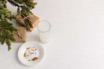 Empty glass of milk and crumb biscuits and a gift under the Christmas tree. The concept of the arrival of Santa Claus.