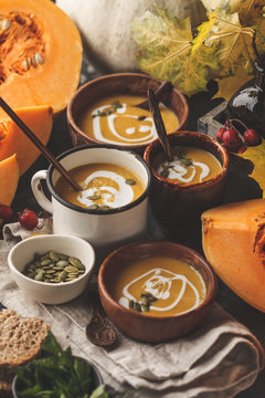 Autumn pumpkin soup puree with cream in cups, the autumn scenery. Healthy vegan food concept.