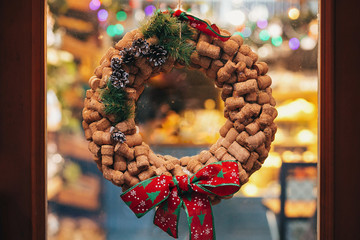 Creative christmas wreath of wine corks, pine cones and red bow on door or window   in european...