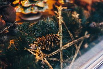 Stylish christmas street decor, golden star ornaments and pine branches with lights in window in european city. Festive decorations and illumination in city center, winter holidays
