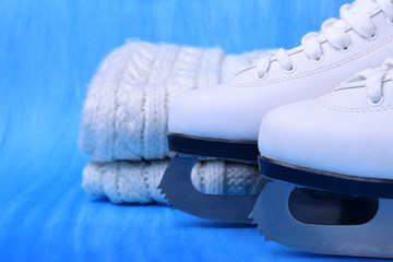 White figure skates and a knitted scarf against the blue background