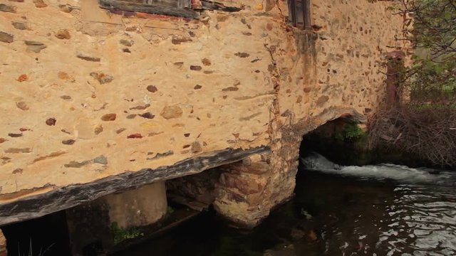 Viejo molino de cereal construido en piedra para fabricar harina,  movido por el agua corriente de un canal
