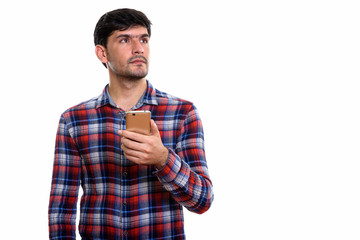 Fototapeta premium Studio shot of young Persian man holding mobile phone while thin