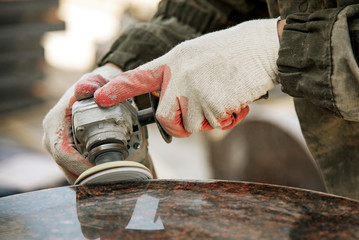 close-up worker in gloves grinds marble with an angle grinder. manufacturing of monuments. working...