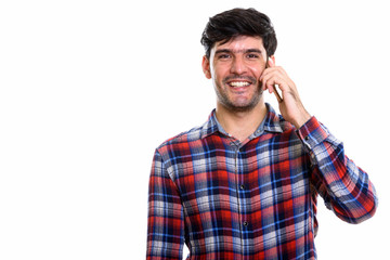 Studio shot of young happy Persian man smiling while talking on 