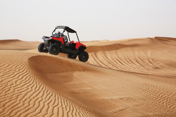 Fototapeta na wymiar Off-road SUV vehicle speeding through sand dunes in the Arabian desert.