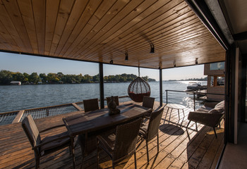 Fototapeta premium Drewniany balkon z miejscem do siedzenia obok rzeki w chatce