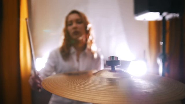 Repetition. Redhead girl plays on drums. Slow motion. Focus on plate