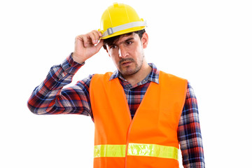 Studio shot of young Persian man construction worker thinking wh