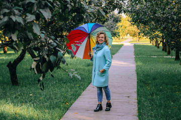 Young beautiful girl walks in the autumn park with a colorful umbrella