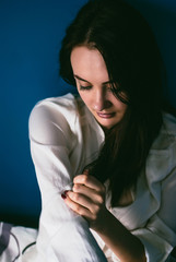 Naklejka premium Pretty pale smiling brunette. Atmospheric portrait of a happy dreaming girl. Blue wall on the background.