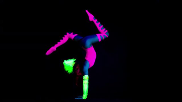 amazing female yoga instructor moving between poses wearing fluorescent clothing under UV black light