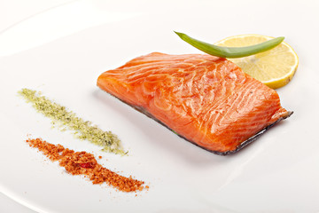 Steak of salmon with lemon on  white plate.