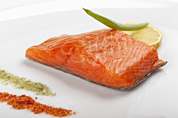 Steak of salmon with lemon on  white plate.