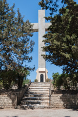 Fototapeta na wymiar The path leading to gigiantic cross. Christ's passion. Wayside Shrine. Greek Island of Rhodes.