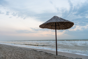 One straw umbrella on the sea beach