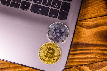 Laptop and bitcoins on a wooden table. Top view