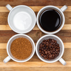 assortment of four white cups of coffee on a saucer grain, instant, brewed and an empty cup on the wooden surface