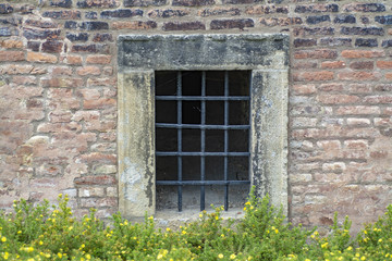 Fototapeta na wymiar A small window on the ground level taken by steel bars