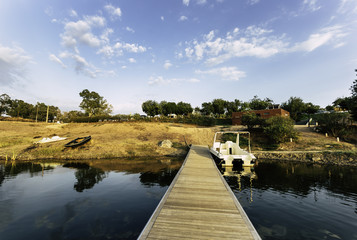 Wooden jetty with moored boat and reflections on lake water