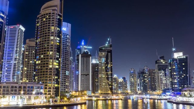 Timelapse in Dubai Marina at night with buzzing nightlife, party boats and modern skyscrapers