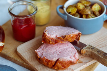 Frischer bayerischer Leberkäse und Breze aus dem Ofen mit Bratkartoffeln im Biergarten Wirtshaus zum Essen