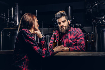 Bearded male and his girlfriend enjoying craft beer during dating at indie brewery.
