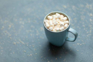 The concept of the New year and Christmas 2019. Hot cocoa with marshmallows in a blue Cup on a blue background with snow flakes. Decor. Postcard