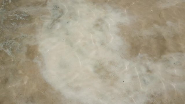 Tourist's hands with salt crystals at the shallow water of Salinas Grandes. Jujuy & Salta provinces, Argentina