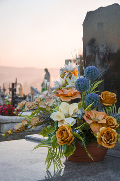 Floral decoration on the grave with a cementary in the background