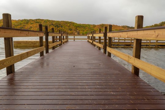 Dramatic closeup view from the end of a dock on a lake with colorful Autumn landscape in background