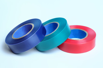 Three rolls of multicolored insulation tape. Isolated on blue background. Blue. Green. Red