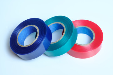 Three rolls of multicolored insulation tape. Isolated on blue background. Blue. Green. Red