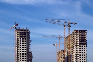 Image of construction of new residential buildings with a variety of construction cranes.