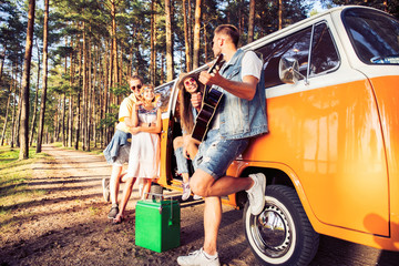 summer holidays, road trip, vacation, travel and people concept - smiling young hippie friends having fun over minivan car.