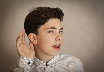 teenager boy  ear and hand as a hearing listen gesture