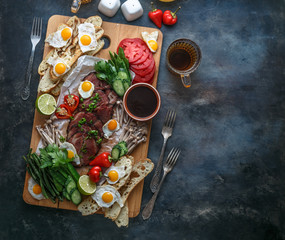 Cutting board with meat, eggs, vegetables, mushrooms, flat lay copy space.