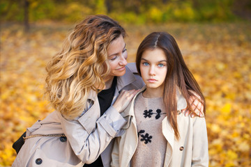 Happy mother and daughter are walking in the autumn park