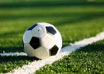 Fototapeta premium classical black and white football ball on the green grass of the field. Soccer game, training, hobby concept. with copy space 