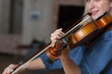 Young beautiful woman violin player looking at camera over instrument on her shoulder holding bow.