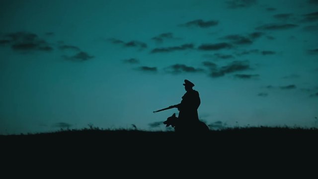 A communist militiaman guarding the border with his dog. Eastern Bloc Countries during the Cold War.
