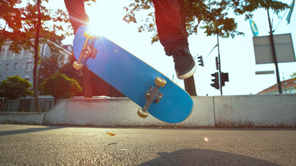 LENS FLARE: Unrecognizable male athlete does a fakie trick with his skateboard.