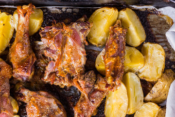 Baked meat with potatoes. Duck meat with golden crust on baking sheet. Cooked in oven dish on parchment. Golden sliced potatoes with chicken meat. Home kitchen