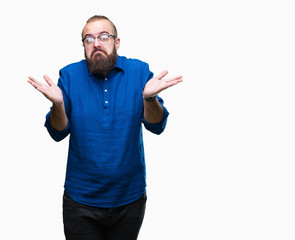 Fototapeta premium Young caucasian hipster man wearing glasses over isolated background clueless and confused expression with arms and hands raised. Doubt concept.