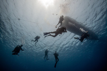 Scuba divers near boat on ocean surface