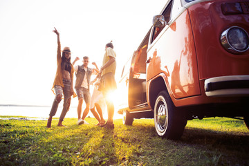 summer holidays, road trip, vacation, travel and people concept - smiling young hippie friends having fun over minivan car